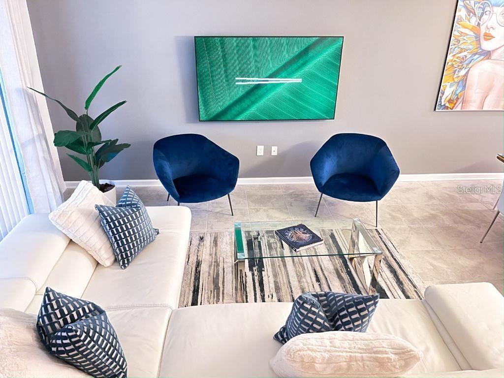 A living room features a white sectional sofa, two blue velvet chairs, and a television — 1139 DROP LANE UNIT 1139, DAVENPORT, FL