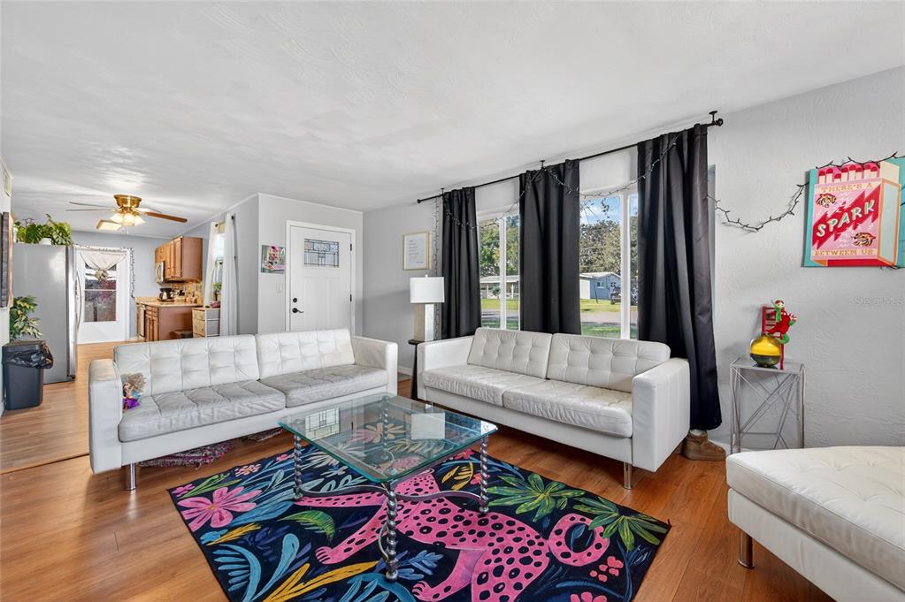 A living room features two white sofas, a glass coffee table, and a colorful rug — 729 N FLAMINGO DRIVE, HOLLY HILL, FL
