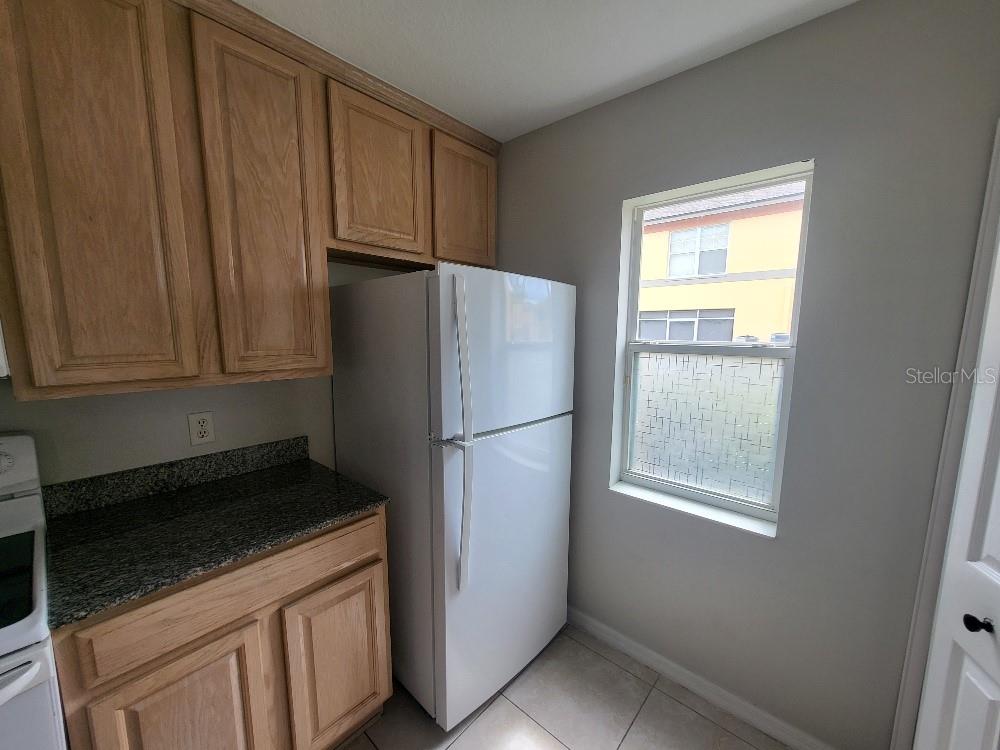 A kitchen features light wood cabinets, granite countertops, a white refrigerator, and a window — 3874 MARINER DRIVE, ST PETERSBURG, FL