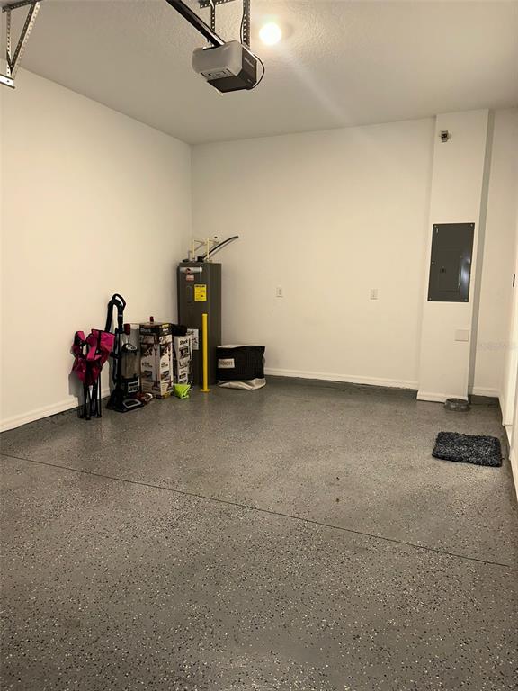 A garage with a gray speckled floor, a water heater, and an electrical panel — 1457 DISCOVERY STREET, DAVENPORT, FL