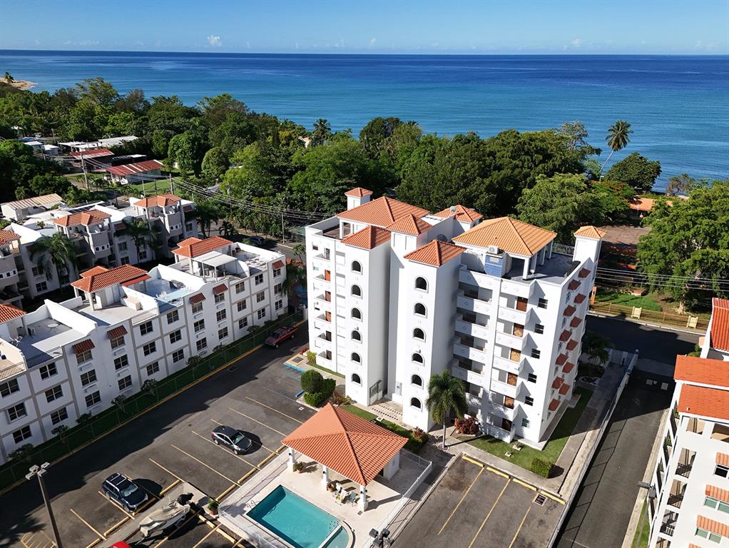 An aerial view shows a multi-story apartment complex with a pool and ocean views — 115 C.CAMBIJA UNIT 4B, RINCON, PR