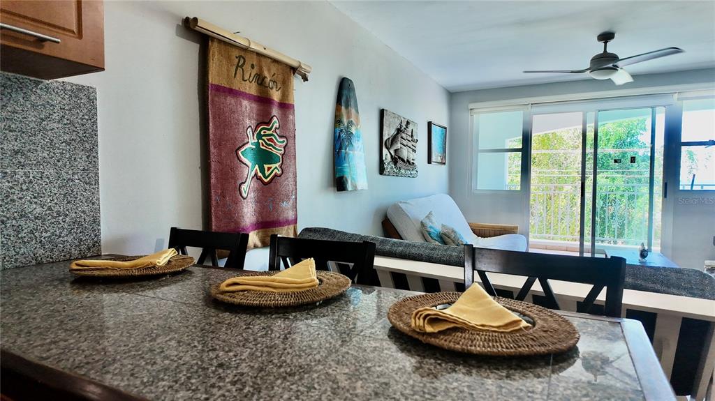 A dining area with a granite-topped counter overlooks a living room with a ceiling fan — 115 C.CAMBIJA UNIT 4B, RINCON, PR