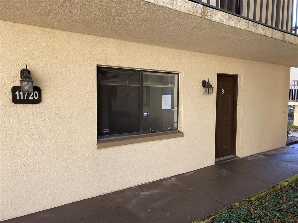 An exterior view of a building entrance with a brown door labeled B and window — 11720 RAINTREE LAKE LANE UNIT B, TAMPA, FL