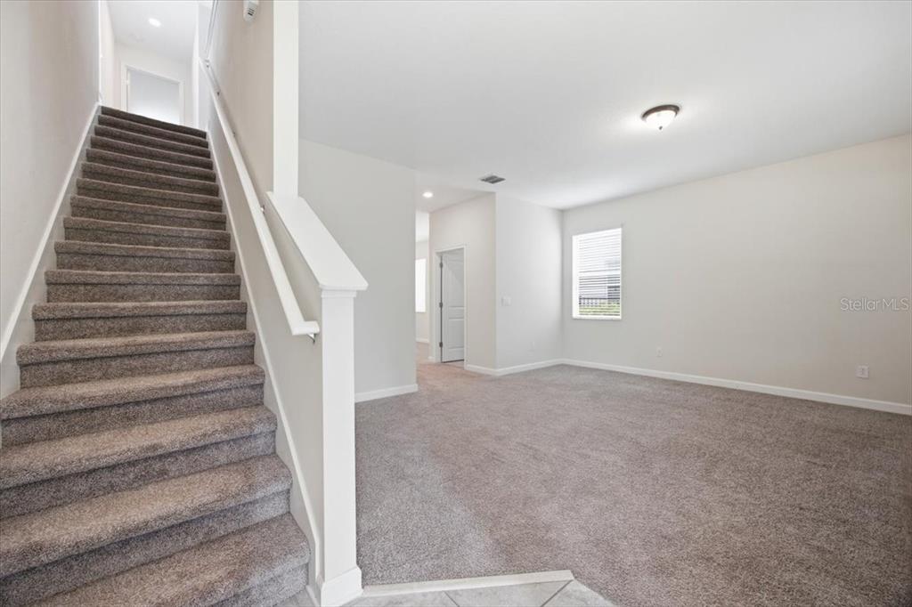 A carpeted staircase leads to an upper level next to an open, carpeted living area — 11854 SONNET AVE, ORLANDO, FL
