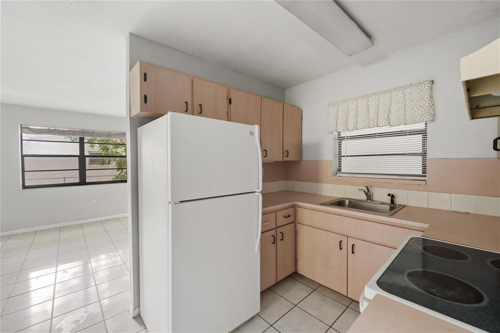 A kitchen features light wood cabinets, white appliances, a stainless steel sink, and tile flooring — 1925 Madison Street # 14, Hollywood FL 33020, HOLLYWOOD, FL