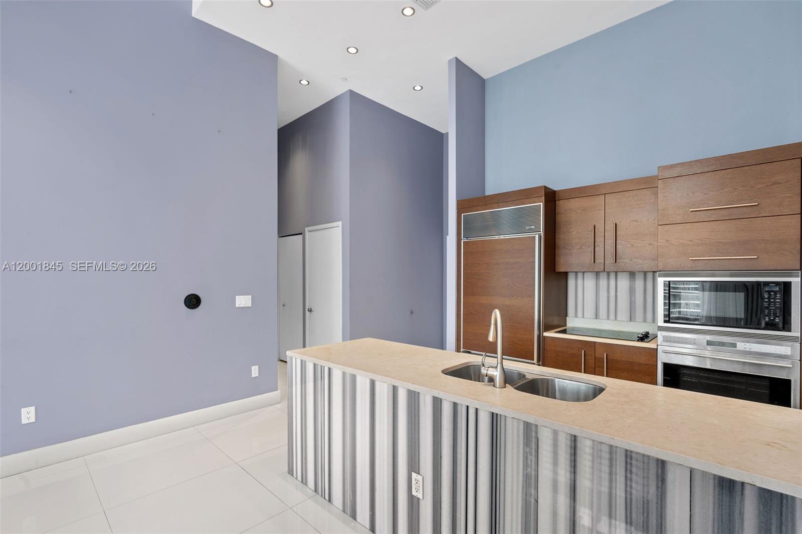 A modern kitchen features wood cabinets, a striped island, and light blue walls — 475 Brickell Ave # 2812, Miami FL 33131, MIAMI, FL