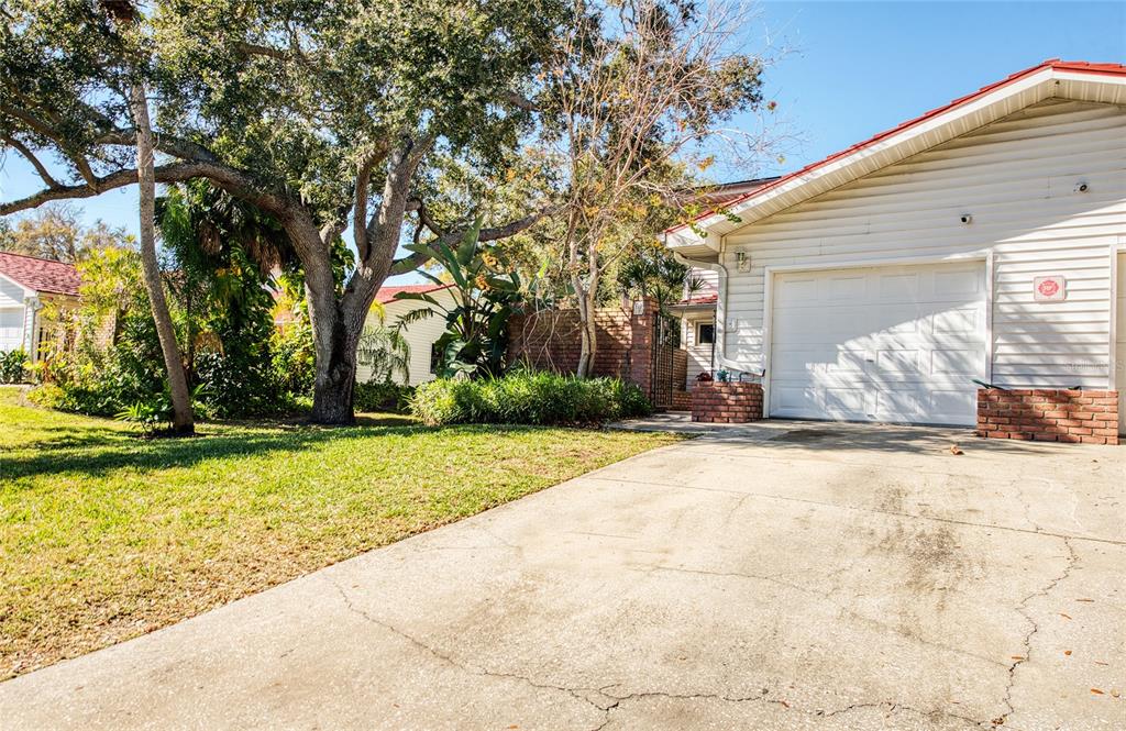 A concrete driveway leads to a white garage door next to a brick-accented house exterior — 1423 WATER VIEW DRIVE W, LARGO, FL