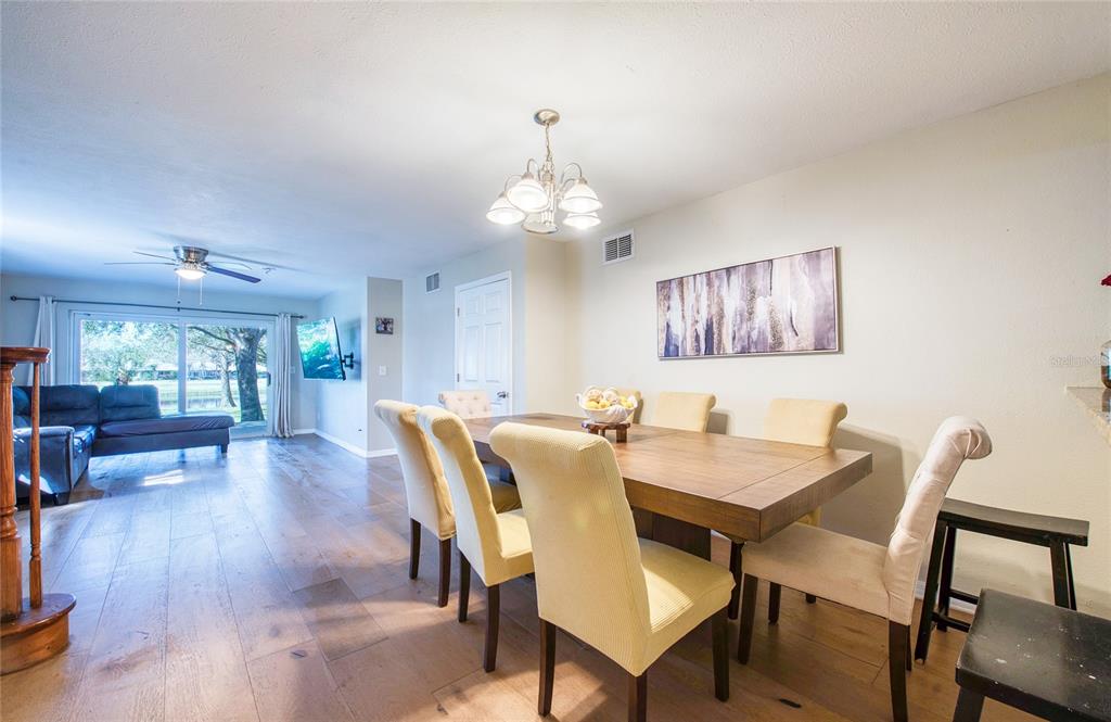A dining area with a wooden table and yellow chairs sits beside a living room — 1423 WATER VIEW DRIVE W, LARGO, FL