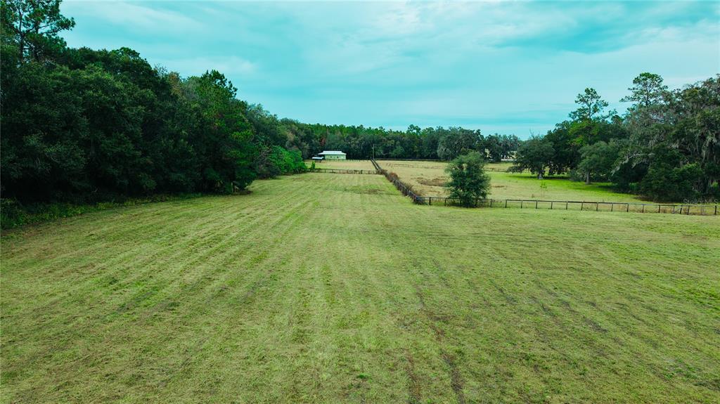 An aerial view shows a large, mowed grassy pasture bordered by trees and a fence — 4600 NW 95TH AVENUE ROAD, OCALA, FL