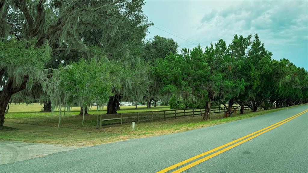 A paved road runs alongside a grassy field bordered by a wooden fence and trees — 4600 NW 95TH AVENUE ROAD, OCALA, FL