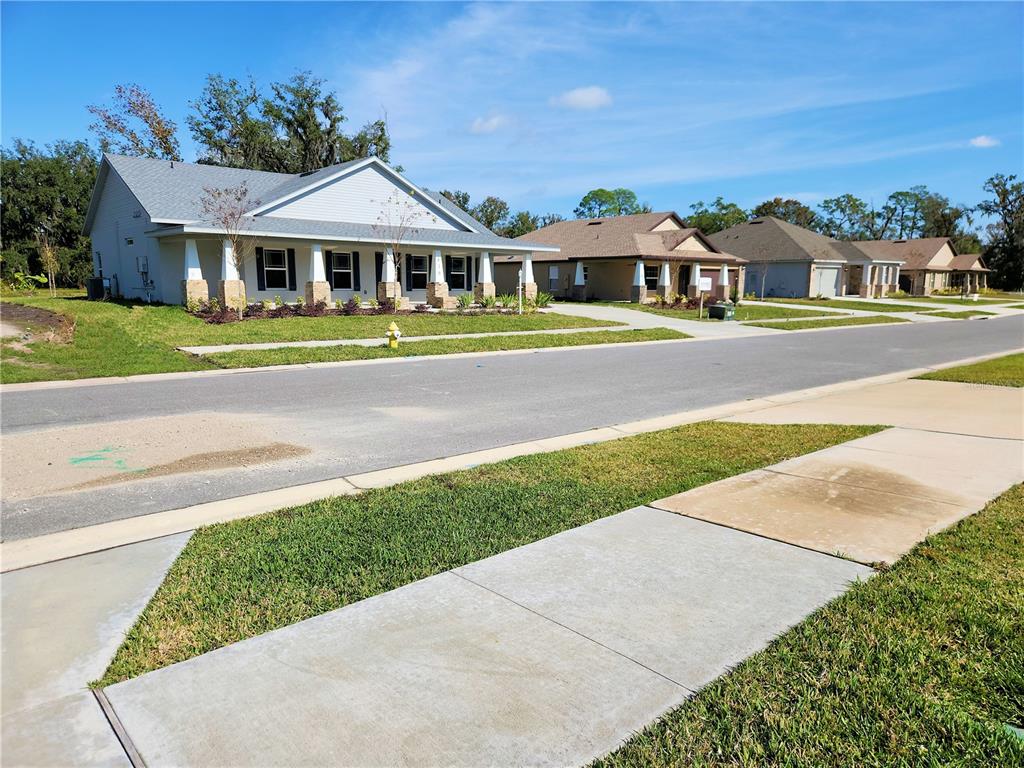A row of newly constructed suburban houses with front porches lines a paved street — 416 SHANNON ESTATES COURT, PLANT CITY, FL