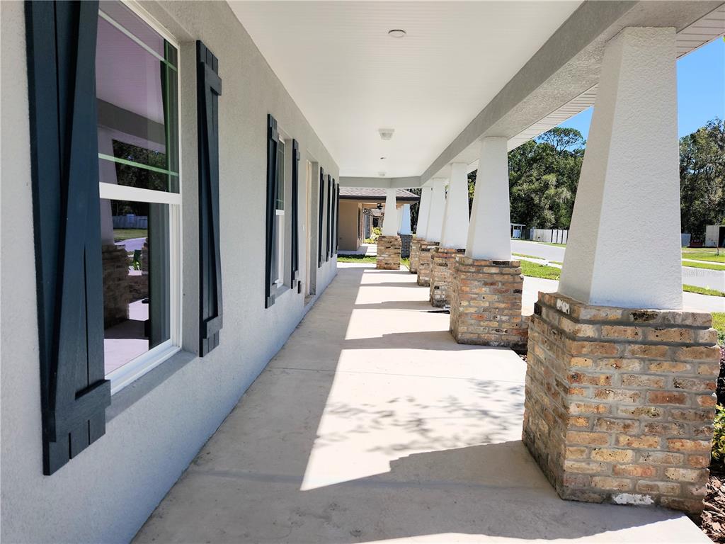 A covered porch features a concrete floor, white columns on brick bases, and dark shutters — 416 SHANNON ESTATES COURT, PLANT CITY, FL
