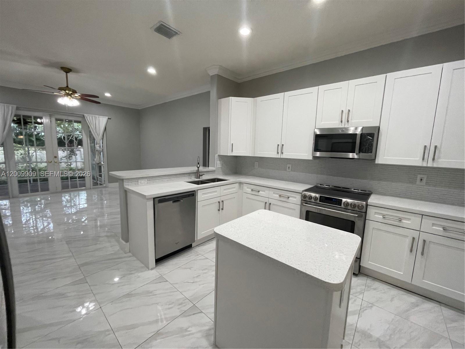 A kitchen features white cabinets, stainless steel appliances, quartz countertops, and light-colored tile flooring — 5263 SW 34th Way, Hollywood FL 33312, HOLLYWOOD, FL