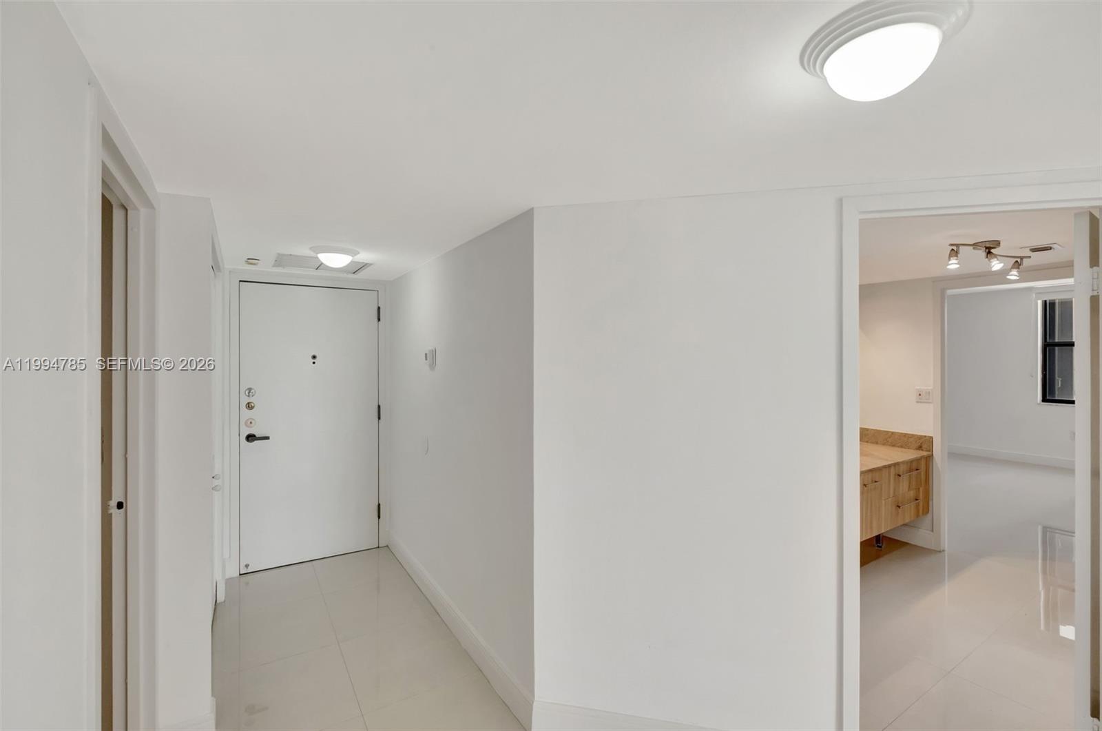 A white-walled entryway features a front door, tiled floors, and a doorway to a bathroom — 2333 Brickell Ave # 305, Miami FL 33129, MIAMI, FL