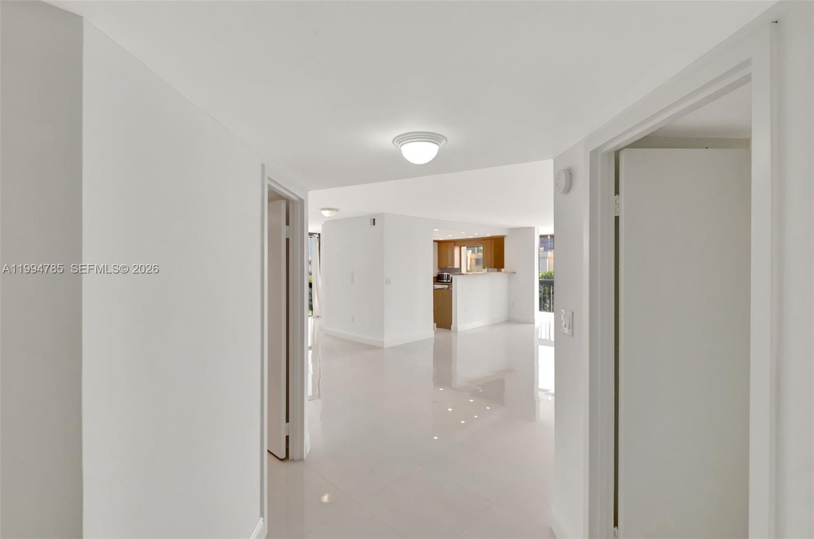A bright hallway with white tile flooring leads into an open living area and kitchen — 2333 Brickell Ave # 305, Miami FL 33129, MIAMI, FL