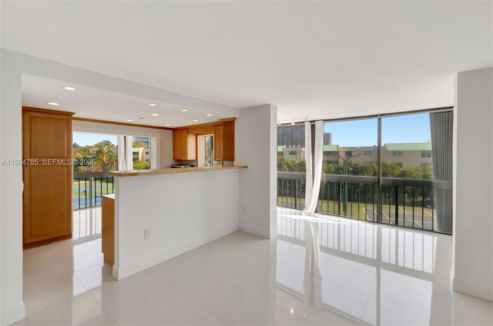 A bright living area with white tile floors, a kitchen breakfast bar, and balcony views — 2333 Brickell Ave # 305, Miami FL 33129, MIAMI, FL