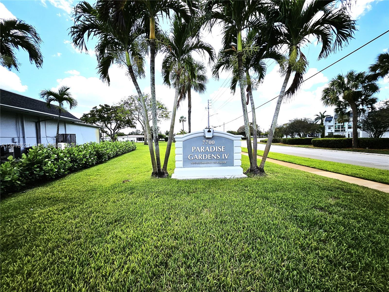 A sign for Paradise Gardens IV stands on a grassy lawn surrounded by palm trees — 1040 NW 73rd Ter, Margate FL 33063, MARGATE, FL