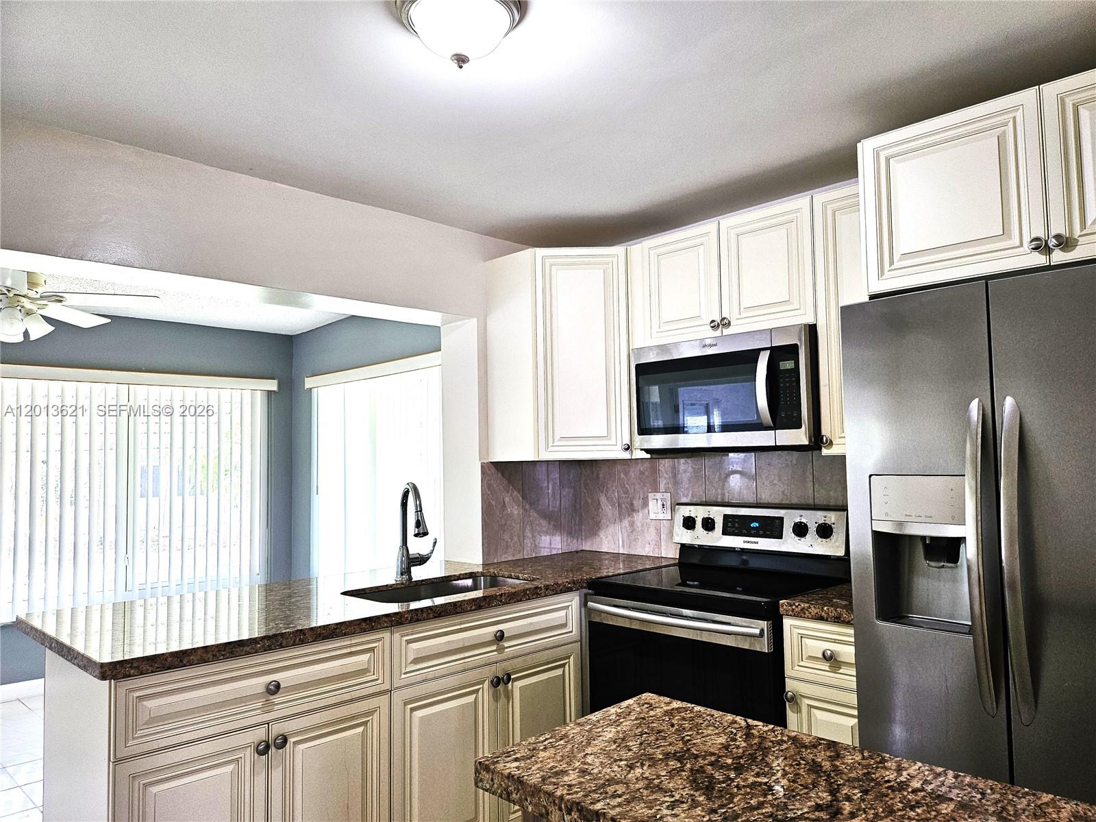 A kitchen features white cabinetry, granite countertops, stainless steel appliances, and a breakfast bar — 1040 NW 73rd Ter, Margate FL 33063, MARGATE, FL