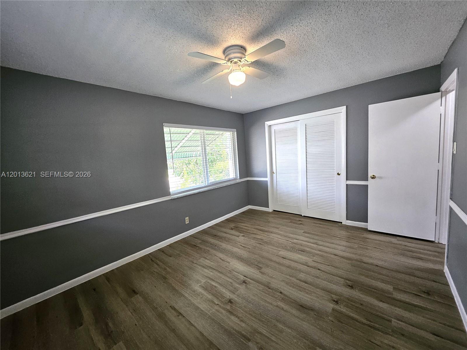 A bedroom with gray walls, white trim, wood-look flooring, a ceiling fan, and white doors — 1040 NW 73rd Ter, Margate FL 33063, MARGATE, FL