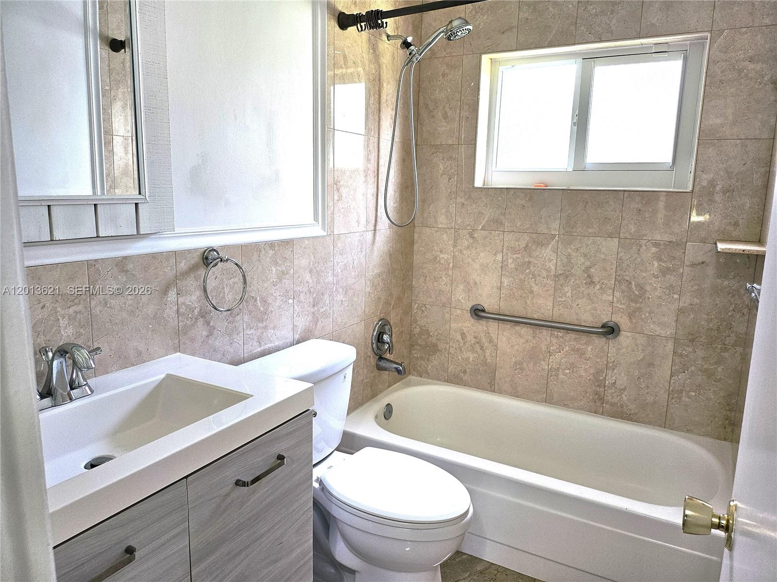 A bathroom features a vanity, toilet, and a tiled bathtub with a shower head — 1040 NW 73rd Ter, Margate FL 33063, MARGATE, FL