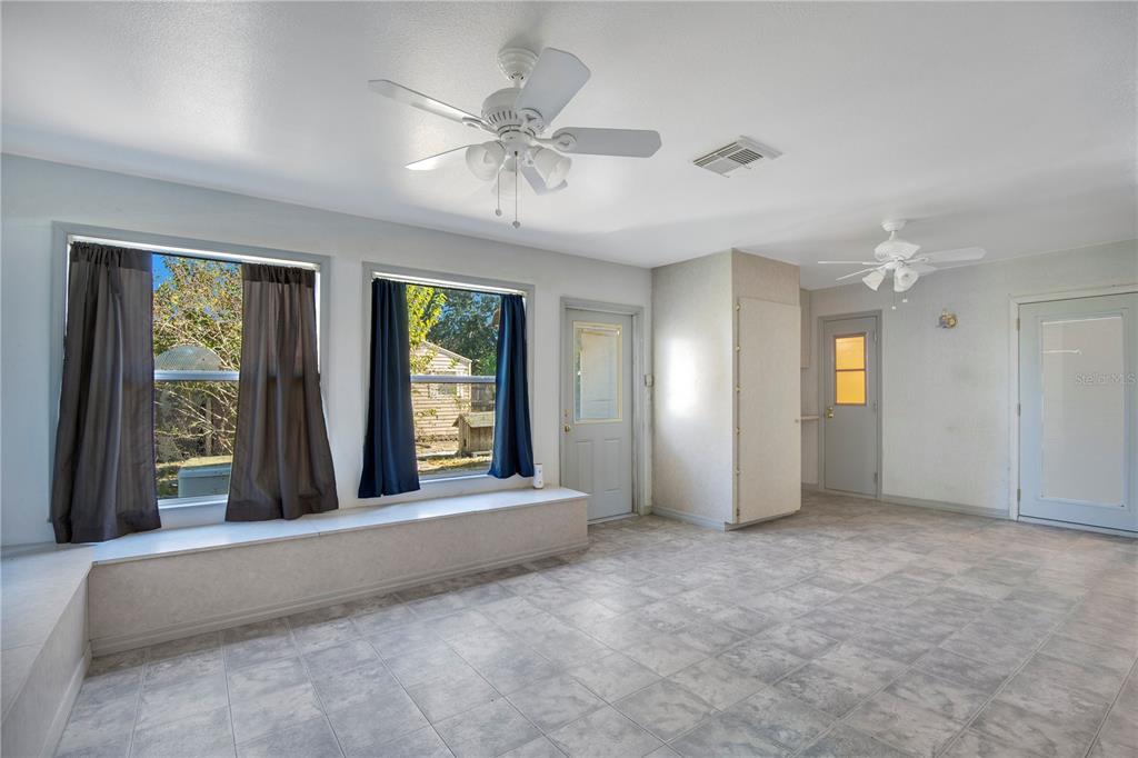 A sunroom features tile flooring, a built-in window bench, two ceiling fans, and three doors — 6019 LONG PEAK DRIVE, ORLANDO, FL
