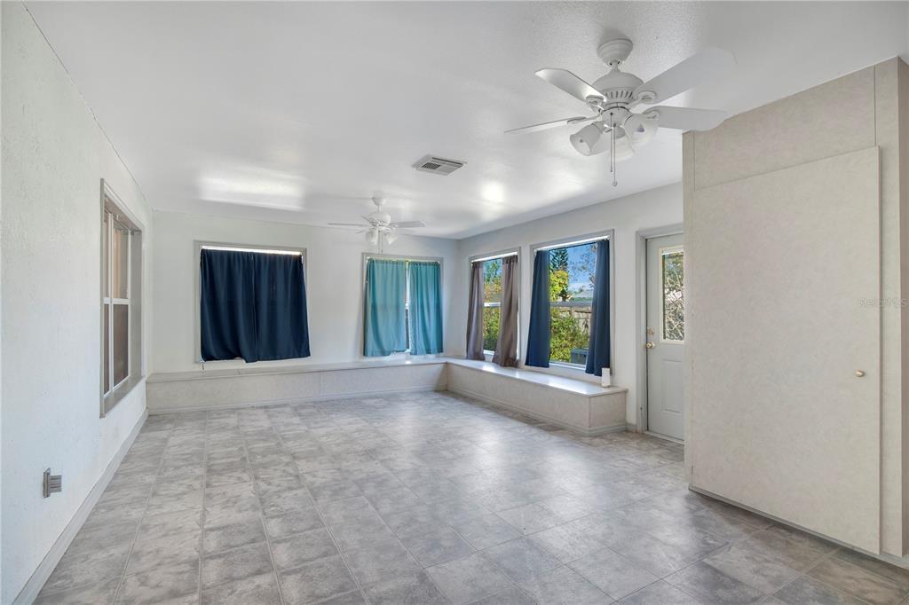 A sunroom with tile flooring, built-in window benches, two ceiling fans, and a glass-paneled door — 6019 LONG PEAK DRIVE, ORLANDO, FL