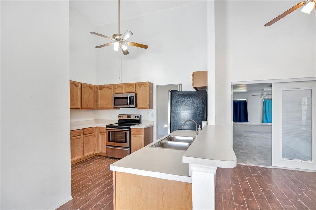 A kitchen with wood cabinets, stainless steel appliances, and a peninsula sink — 6019 LONG PEAK DRIVE, ORLANDO, FL