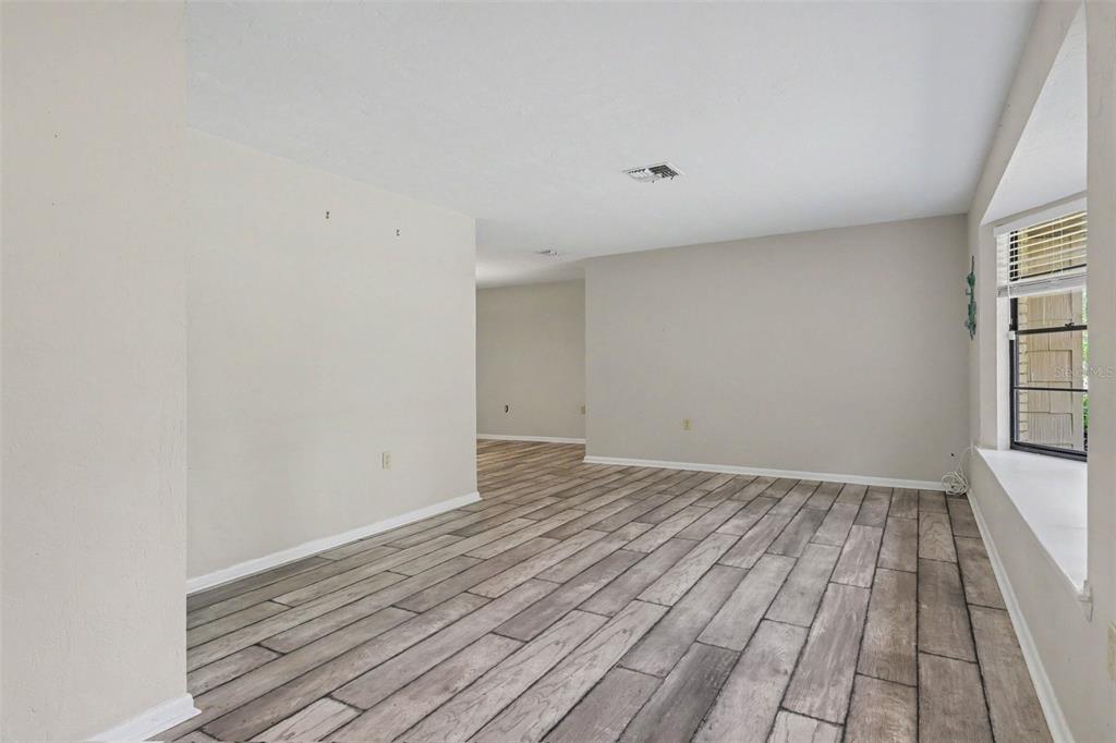 An empty room with light gray walls, wood-look tile flooring, and a large bay window — 9491 SW 200TH COURT, DUNNELLON, FL