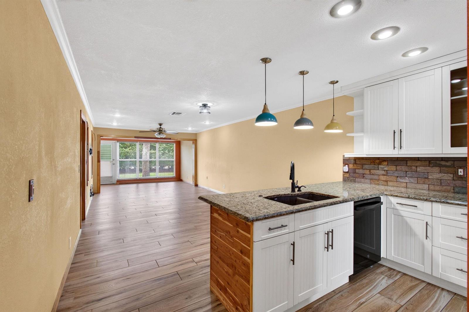 A kitchen with white cabinets and a granite island overlooks an open-concept living area — 2830 SW 15th Street # a, Delray Beach FL 33445, DELRAY BEACH, FL
