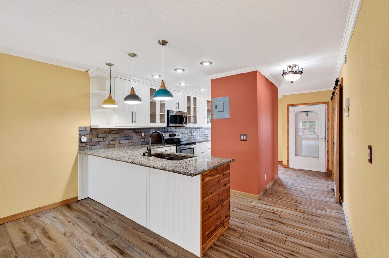 A kitchen with a granite-topped island, white cabinets, and a red accent wall — 2830 SW 15th Street # a, Delray Beach FL 33445, DELRAY BEACH, FL