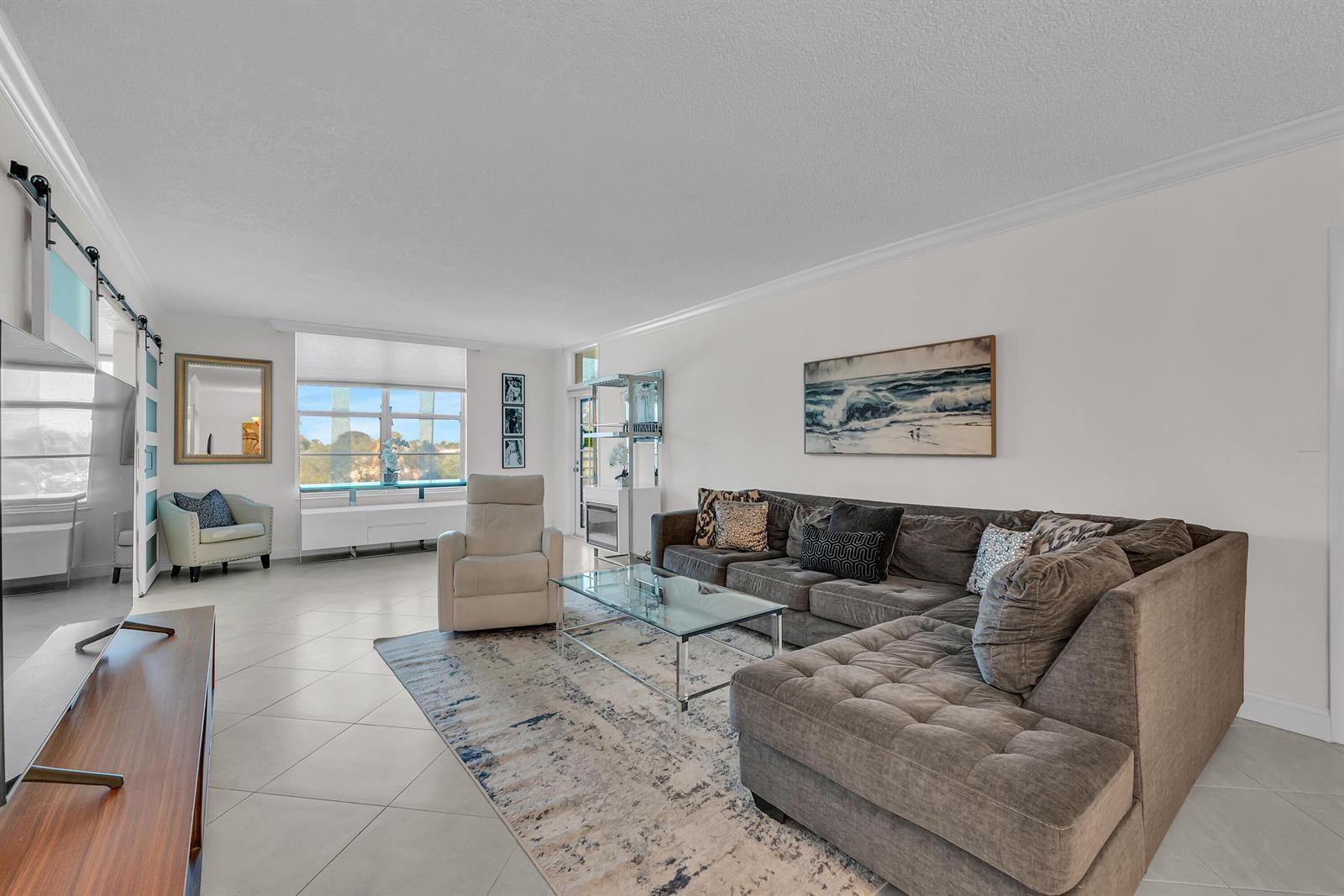 A living room features a grey sectional sofa, a glass coffee table, and tile flooring — 2851 S Ocean Boulevard # P, Boca Raton FL 33432, BOCA RATON, FL