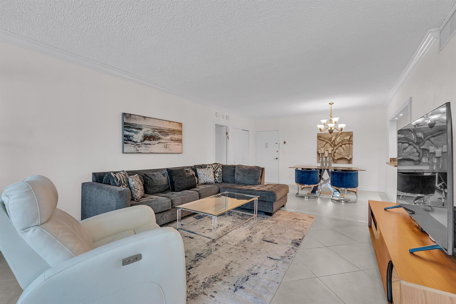 A living and dining area features a gray sectional sofa, glass coffee table, and blue chairs — 2851 S Ocean Boulevard # P, Boca Raton FL 33432, BOCA RATON, FL