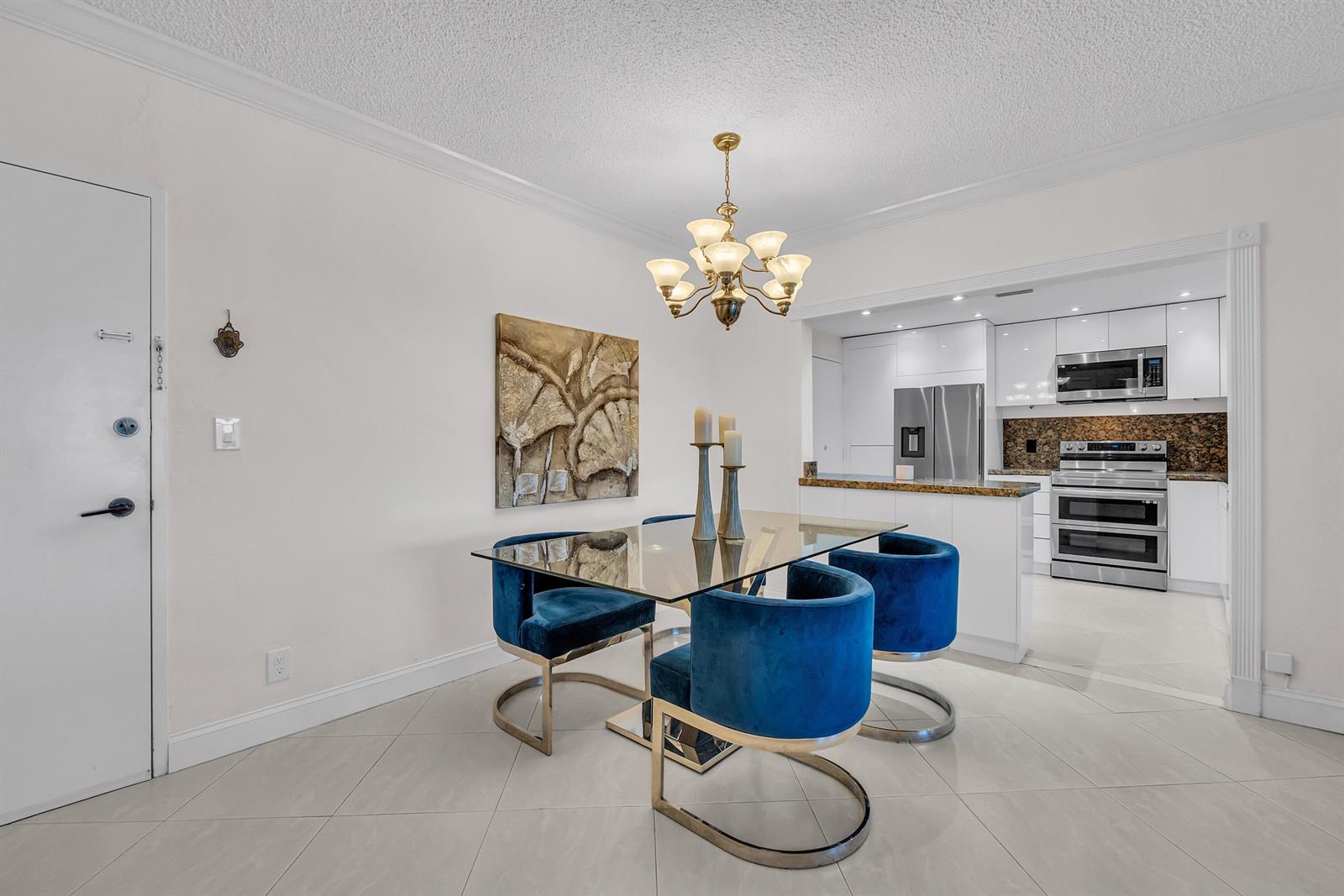 A dining area features a glass table, blue velvet chairs, and an adjacent modern kitchen — 2851 S Ocean Boulevard # P, Boca Raton FL 33432, BOCA RATON, FL