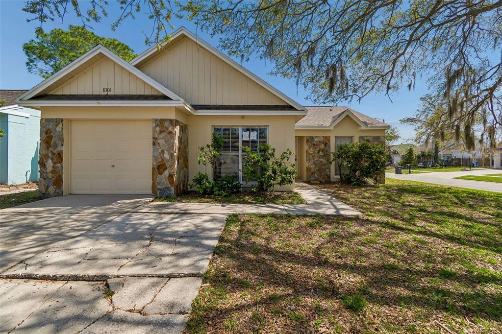 A single-story house with a beige exterior, stone accents, and a concrete driveway — 8301 IBERIA PLACE, TAMPA, FL