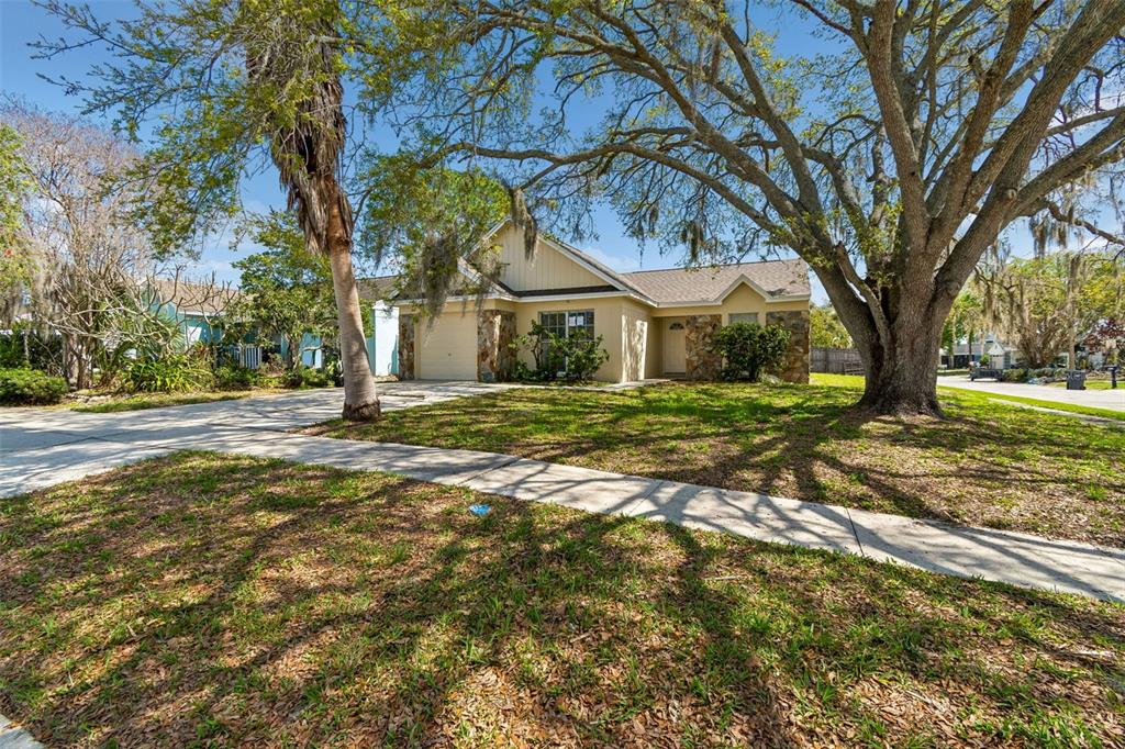 A single-story house with stone accents, a garage, and large trees in the front yard — 8301 IBERIA PLACE, TAMPA, FL