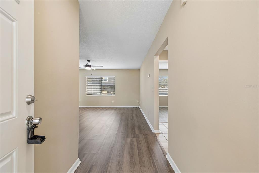 An entryway leads into a living room with wood-look flooring and a ceiling fan — 8301 IBERIA PLACE, TAMPA, FL
