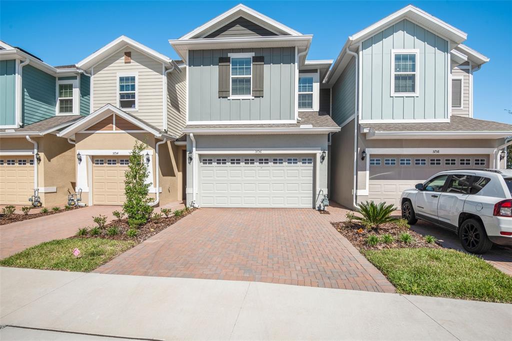 A row of three attached townhomes with paved driveways, garages, and varied siding colors — 5756 SPOTTED HARRIER WAY, LITHIA, FL