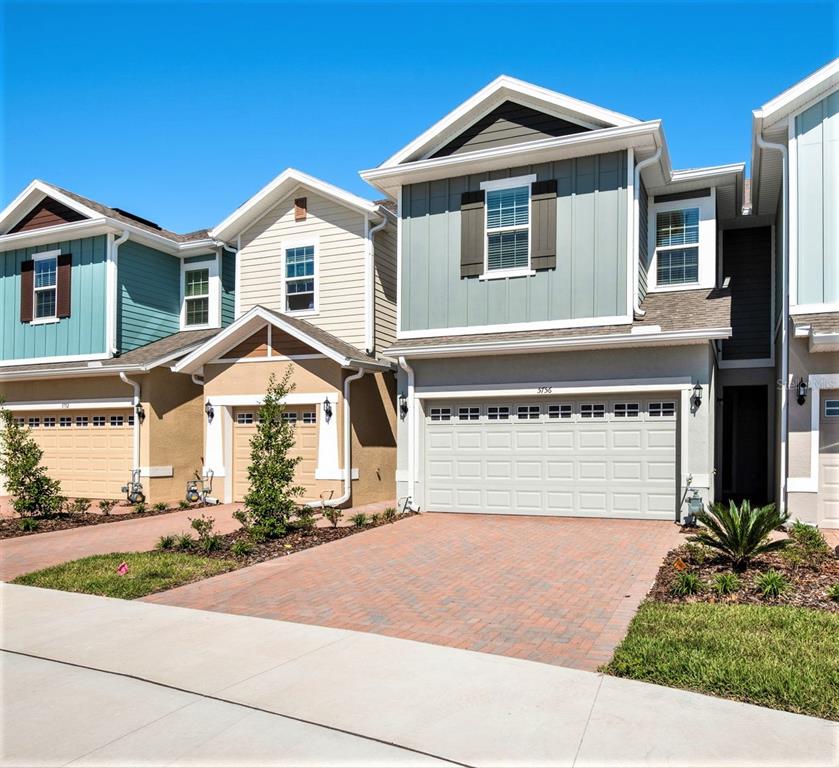 A row of three modern two-story townhouses with attached garages and brick paver driveways — 5756 SPOTTED HARRIER WAY, LITHIA, FL