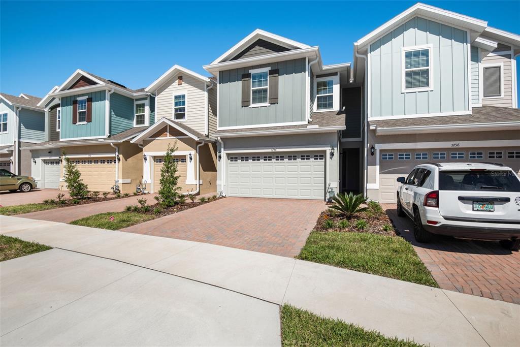 A row of modern townhouses with paved driveways and attached garages under a clear sky — 5756 SPOTTED HARRIER WAY, LITHIA, FL