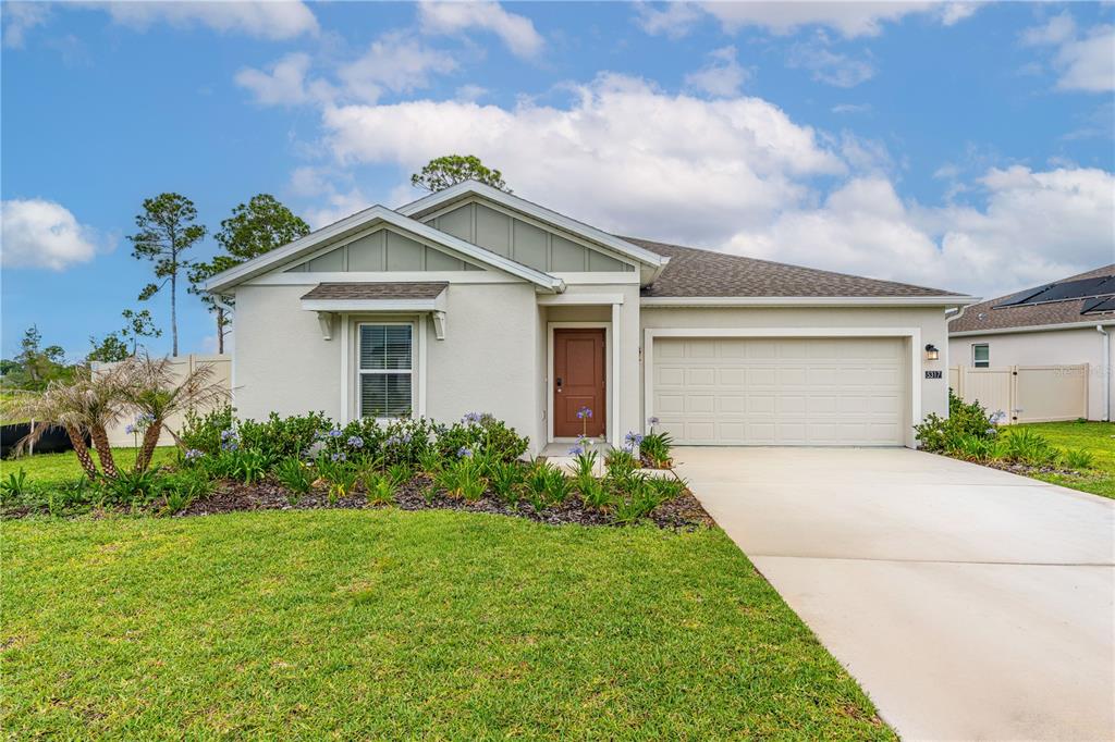 A single-story suburban house with a beige stucco exterior, brown front door, and two-car garage — 5317 DIAMONDLEAF DRIVE, EDGEWATER, FL