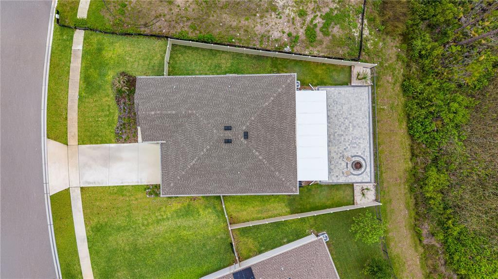 An aerial view shows a house with a shingled roof, driveway, and a paved patio — 5317 DIAMONDLEAF DRIVE, EDGEWATER, FL