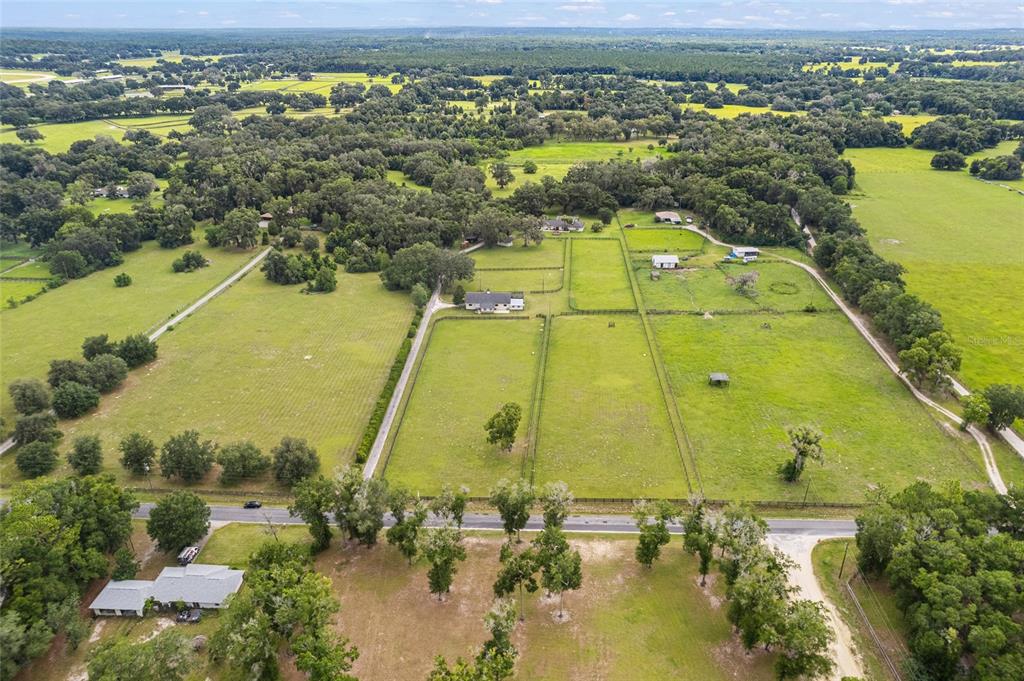 An aerial view shows a rural property with fenced pastures, several houses, and surrounding trees — 11851 SW 38TH STREET, OCALA, FL