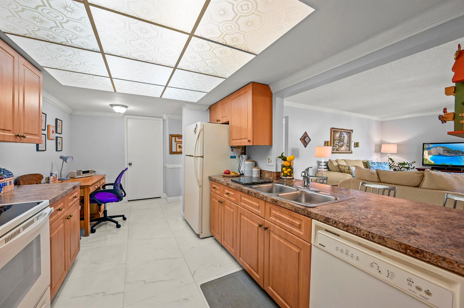 A kitchen with wood cabinets, laminate countertops, and a drop ceiling opens to a living area — 750 Egret Circle # 6509, Delray Beach FL 33444, DELRAY BEACH, FL