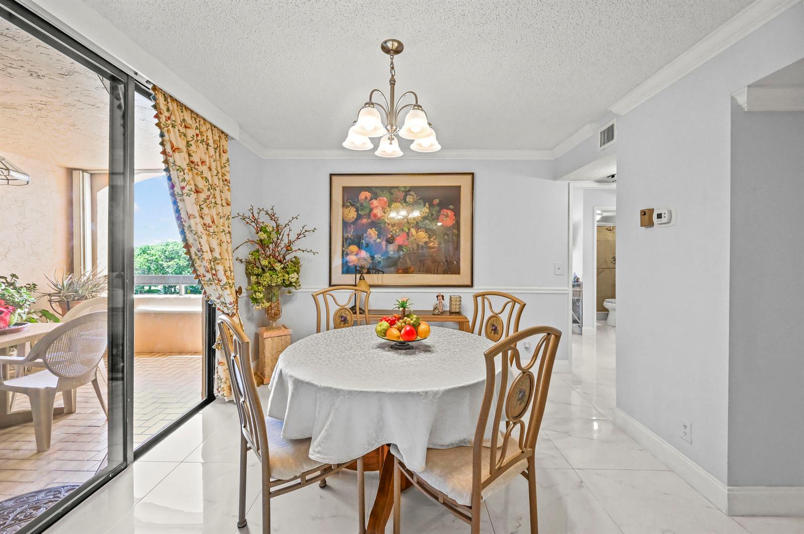 A dining room with a round table, four chairs, a chandelier, and a sliding glass door — 750 Egret Circle # 6509, Delray Beach FL 33444, DELRAY BEACH, FL