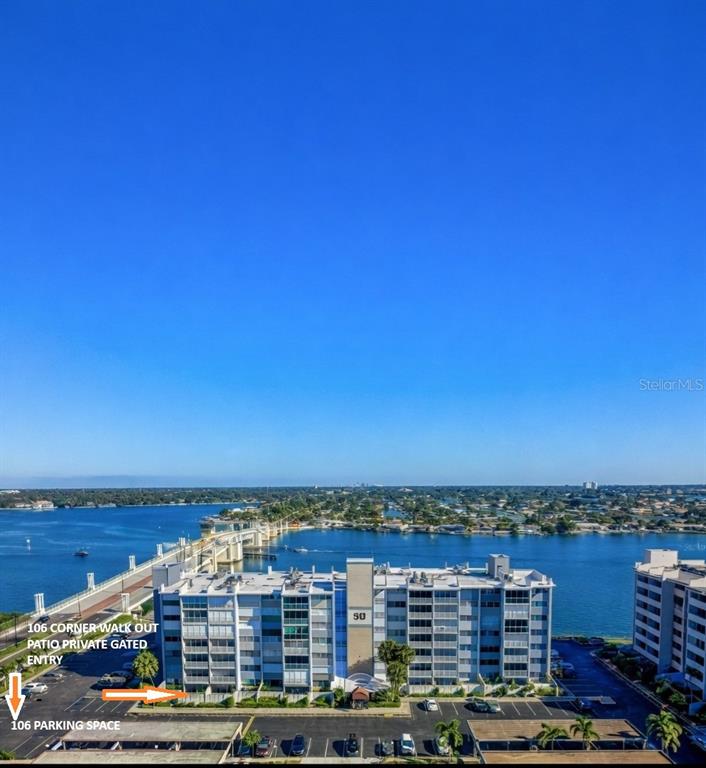 An aerial view shows a multi-story waterfront apartment building with a designated parking space — 500 TREASURE ISLAND CAUSEWAY UNIT 106, TREASURE ISLAND, FL