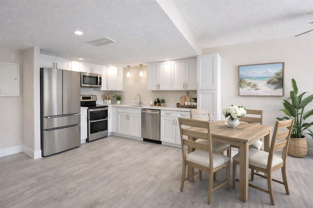 A kitchen with white cabinets, stainless steel appliances, and a wooden dining set — 500 TREASURE ISLAND CAUSEWAY UNIT 106, TREASURE ISLAND, FL