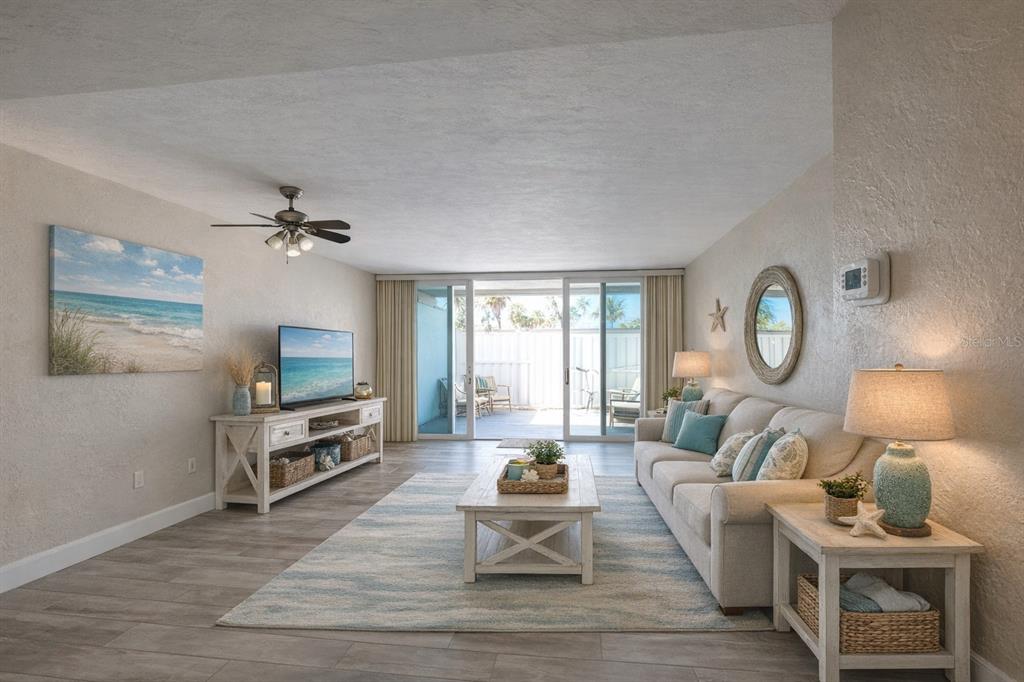 A living room features a beige sofa, a coffee table, and sliding doors to a patio — 500 TREASURE ISLAND CAUSEWAY UNIT 106, TREASURE ISLAND, FL