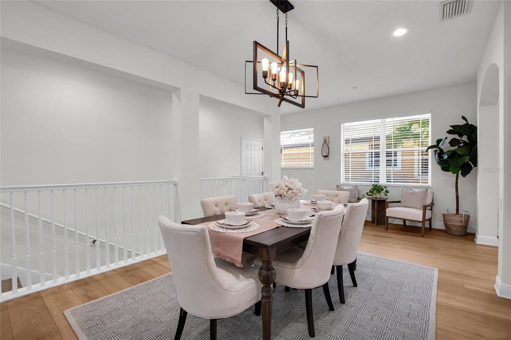 A dining room with a wooden table, upholstered chairs, a chandelier, and light wood flooring — 6508 MOORINGS POINT CIRCLE UNIT 201, LAKEWOOD RANCH, FL
