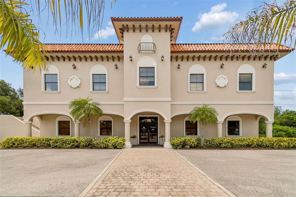 A two-story beige commercial building features a tiled roof, arched entryway, and symmetrical window placement — 6730 W LINEBAUGH AVENUE, TAMPA, FL