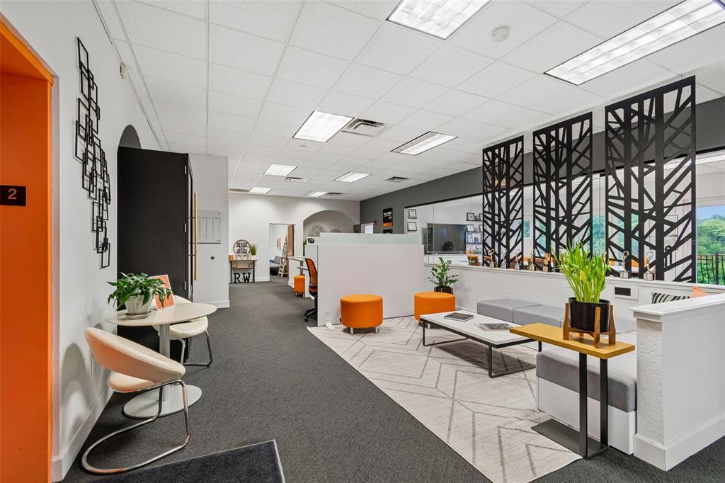 A modern office waiting area features gray carpeting, orange ottomans, and decorative black metal screens — 6730 W LINEBAUGH AVENUE, TAMPA, FL